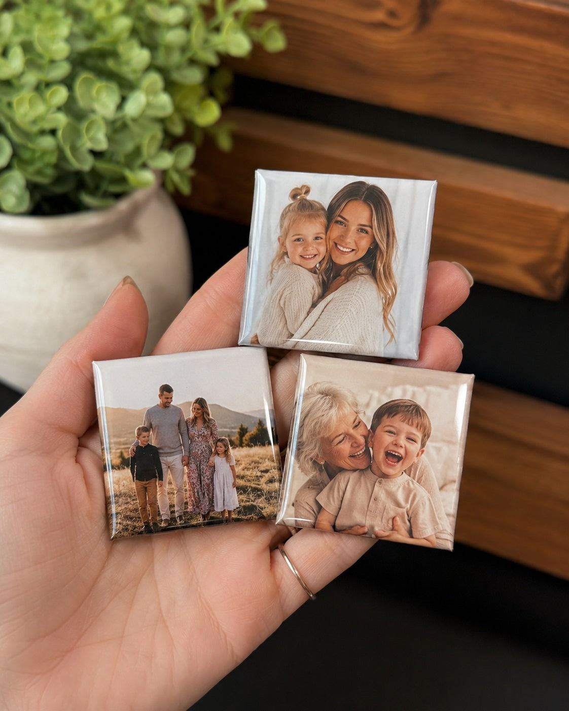 A hand holding three MagMems personalised photo magnets to show their square size and finish